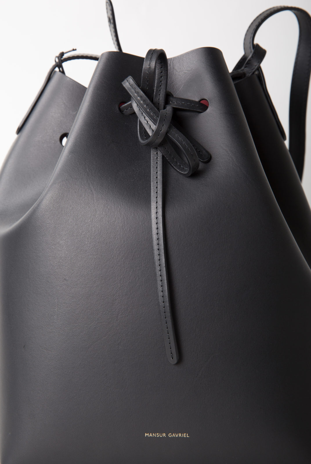 Sac seau italien en cuir tanné végétal noir avec intérieur vernis mat rouge. Sangle réglable. Fabriqué en Italie.