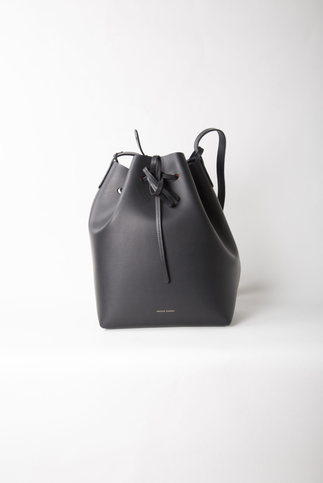 Sac seau italien en cuir tanné végétal noir avec intérieur vernis mat rouge. Sangle réglable. Fabriqué en Italie.